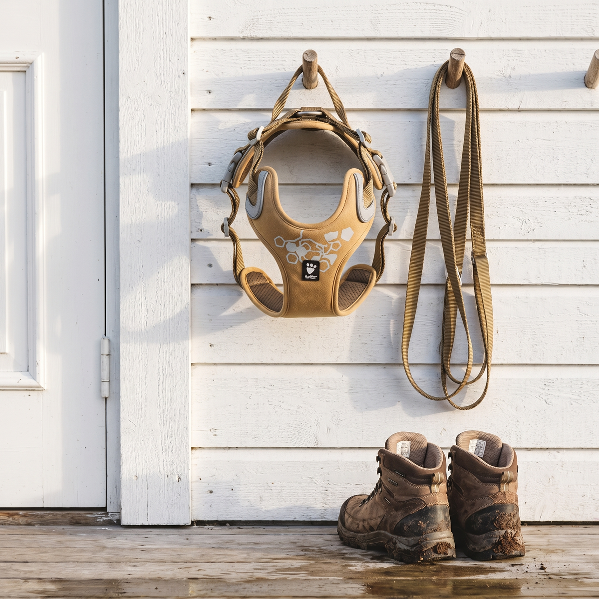 Hurtta Weekend Warrior dog harness in Desert hanging by the front door with a lead and boots