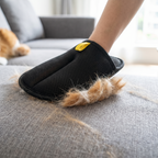 Pet hair removal mitt sweeping fur off a sofa cushion
