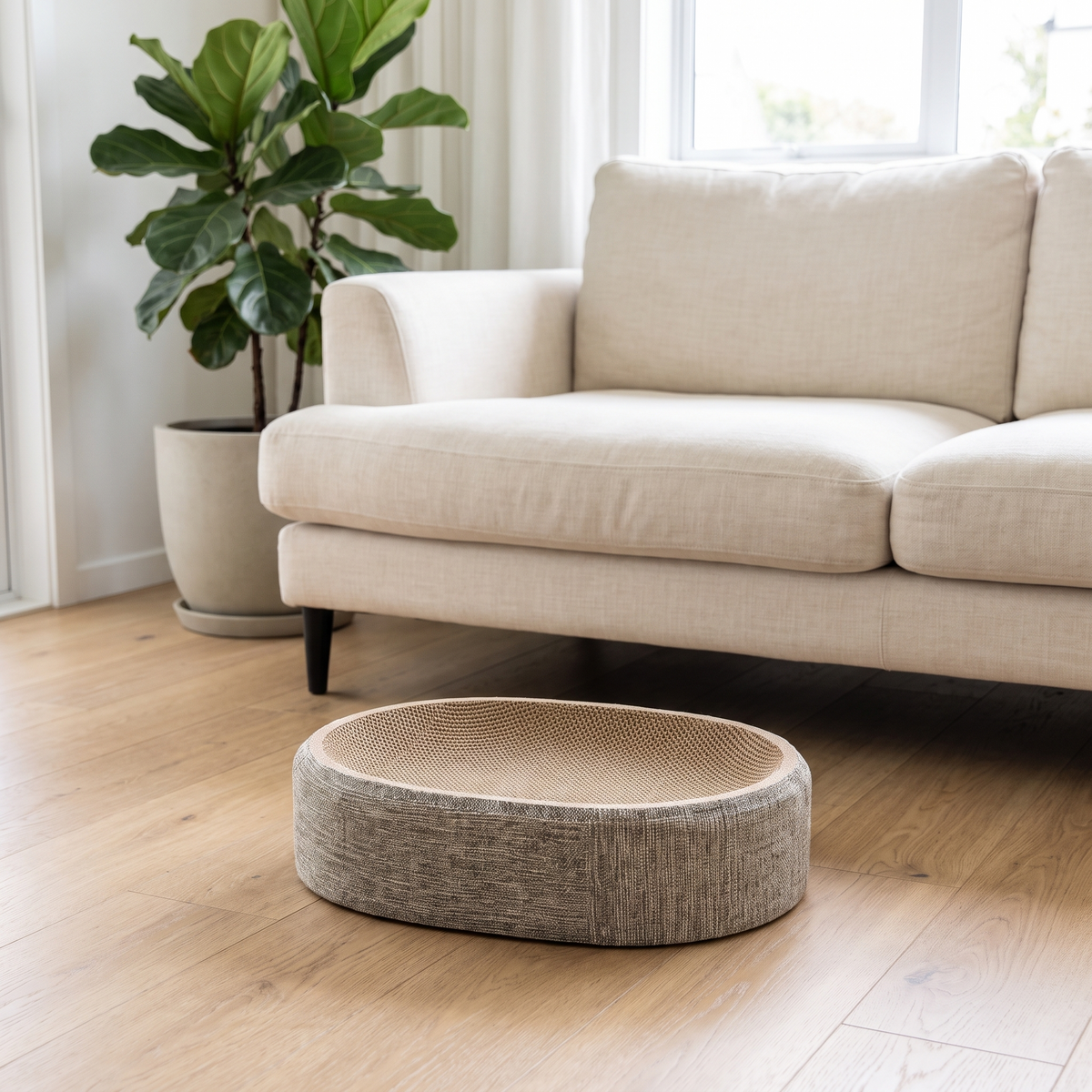 Oval sisal cat scratcher bed on an oak floor in front of a sofa